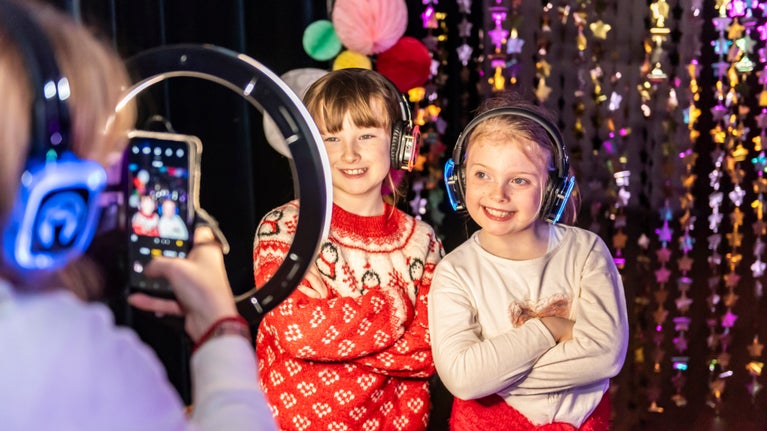 Children smiling while having photo taken with headphones at silent disco at Plas Newydd